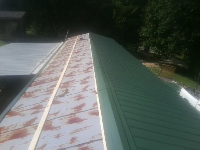 Old rusted panels beside newly installed green metal roofing — Wind Damage Roof Repair by Roofing Brothers in Harrisonville