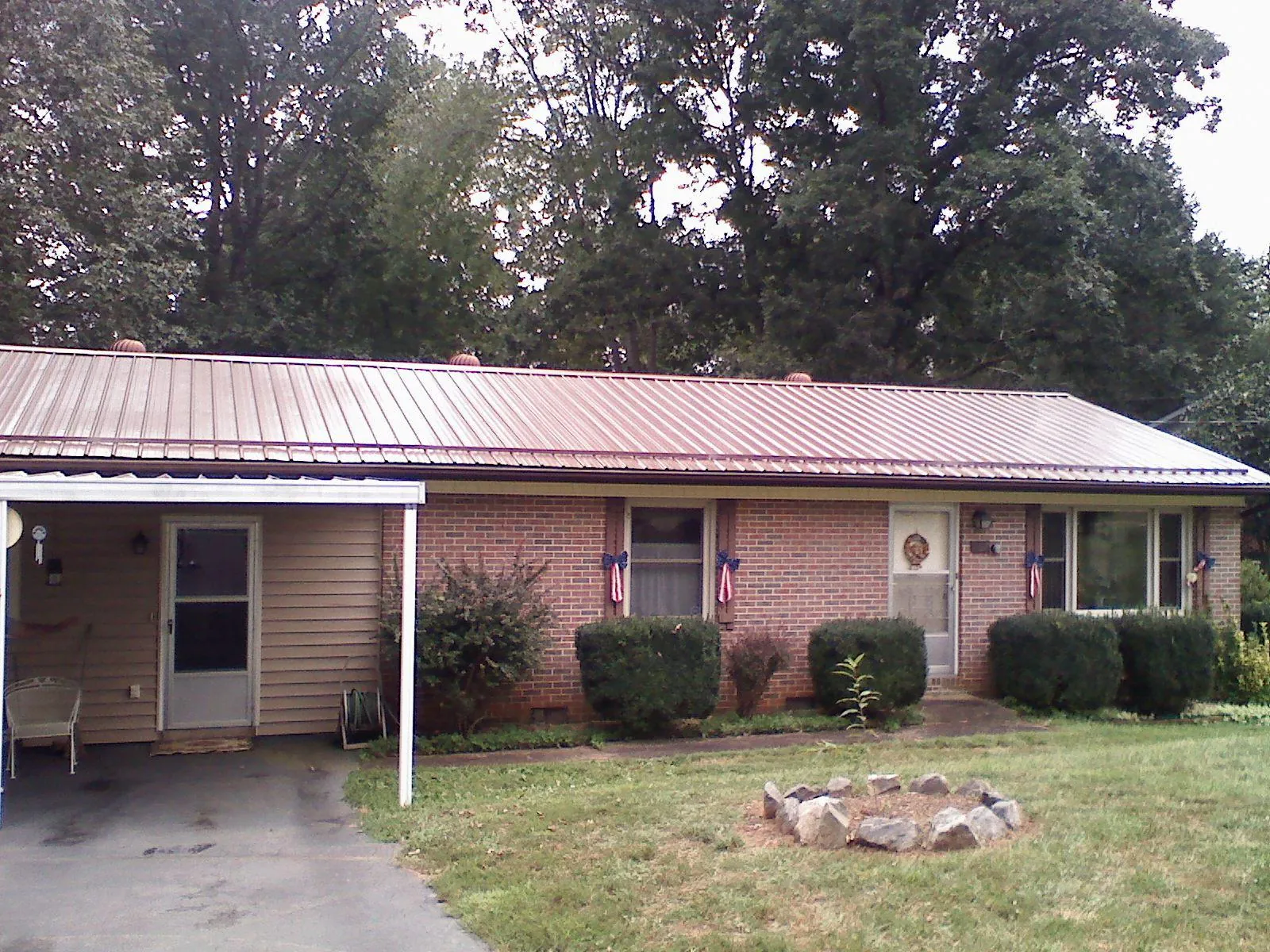 Bronze metal roof and carport on a brick ranch home — Roof Repair work by our crew in Harrisonville