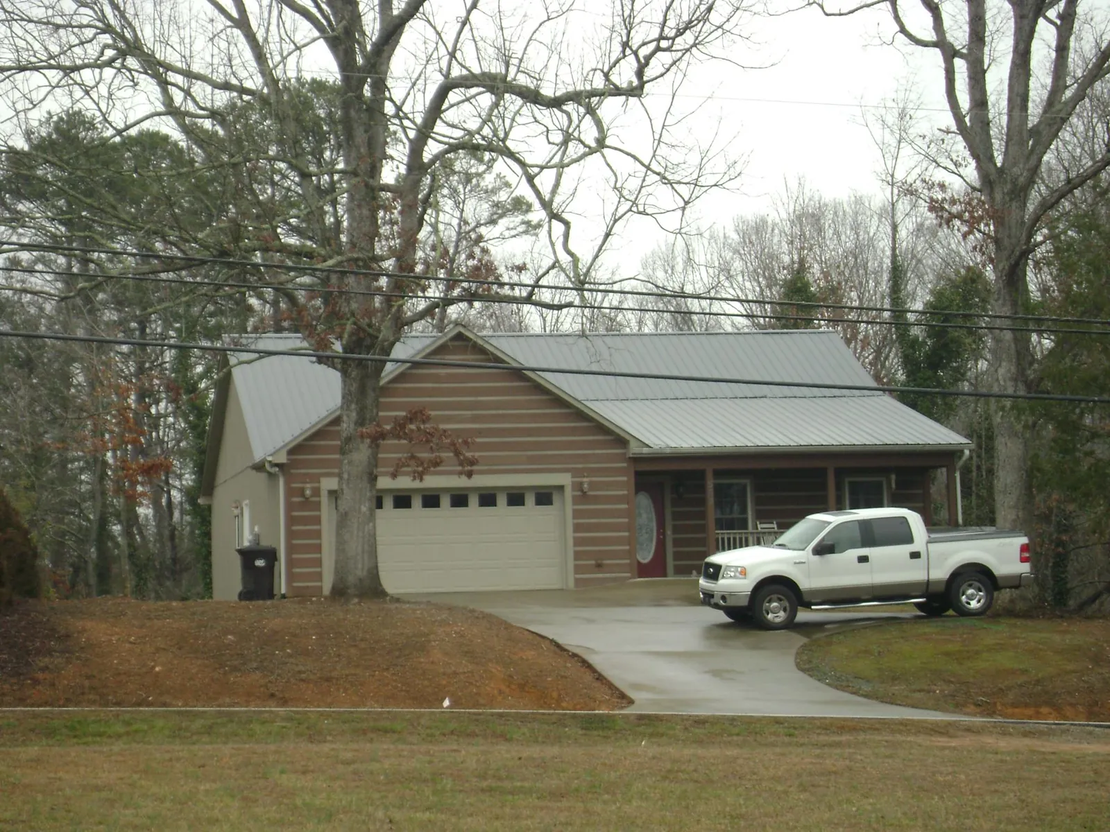 Gray metal roof on a log sided house with an attached two car garage in Harrisonville